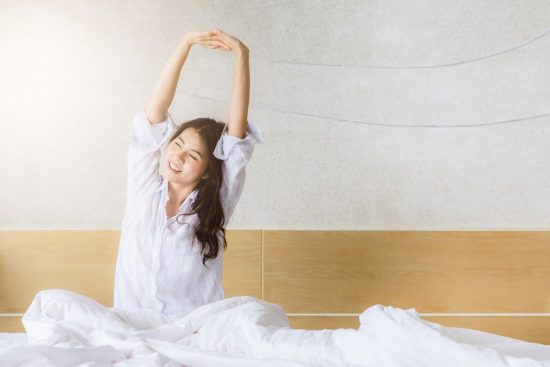 ベッドで伸びをする女性