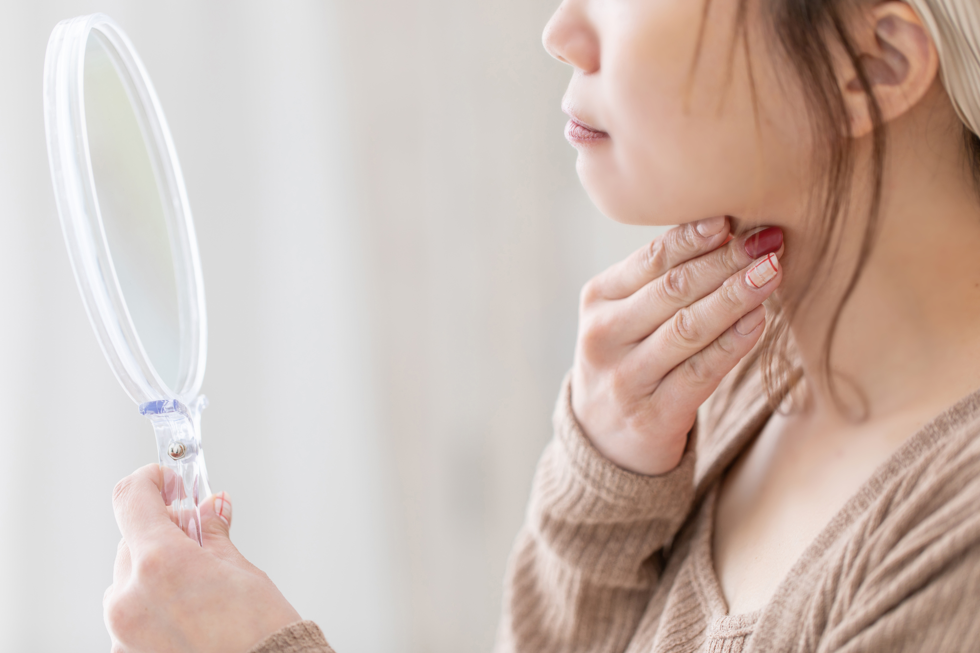 鏡で二重あごを確認する女性