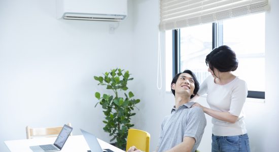 疲れた旦那の肩をマッサージする女性