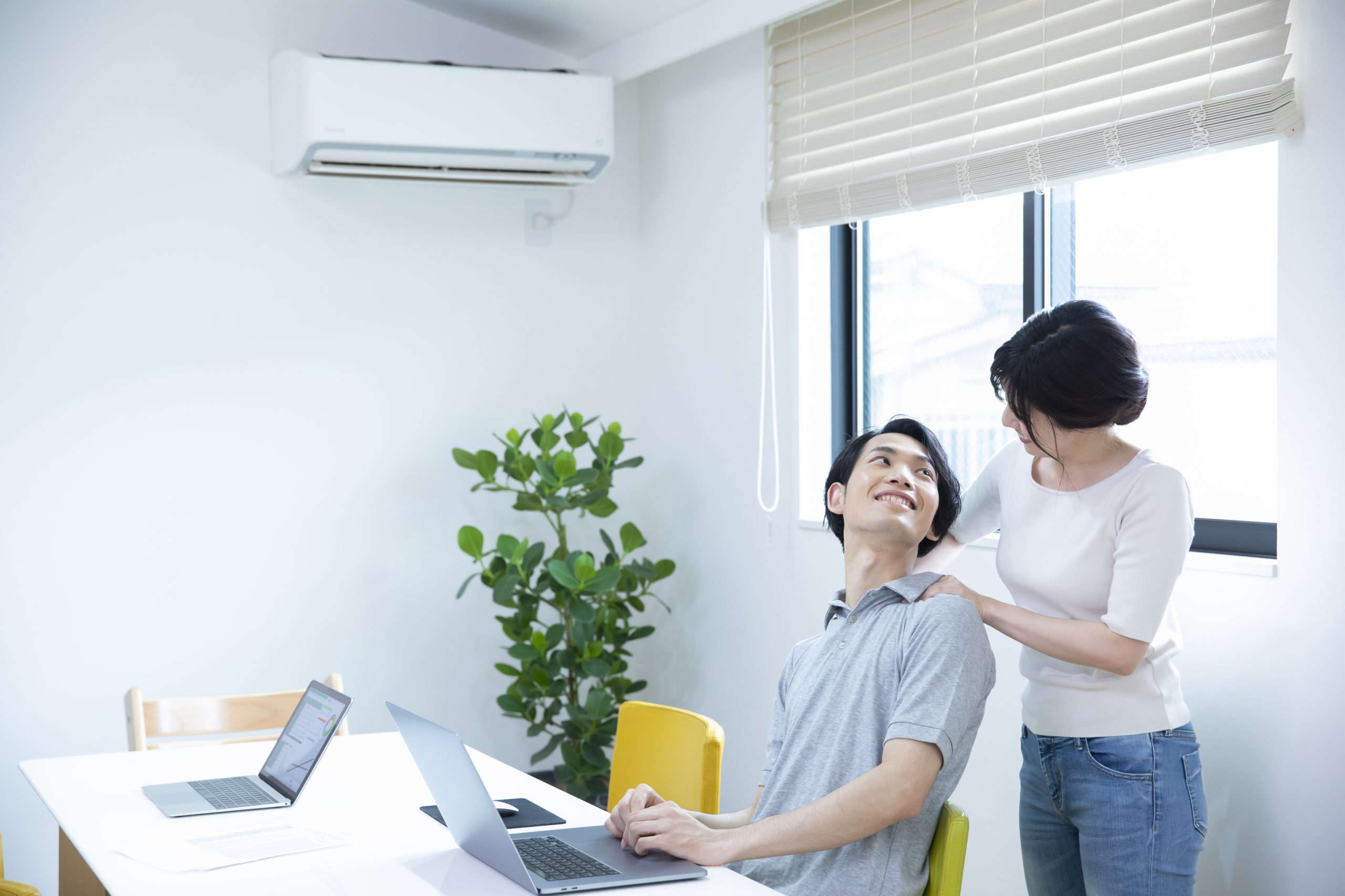 疲れた旦那の肩をマッサージする女性