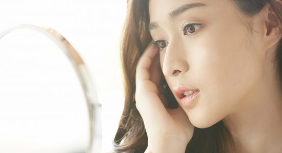 鏡で顔の歪みをチェックする女性