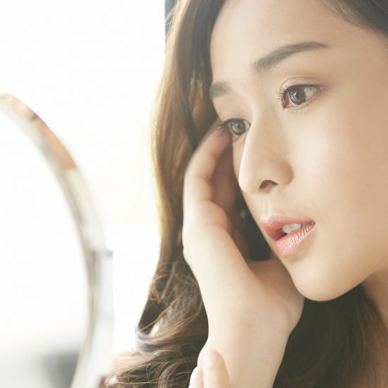 鏡で顔の歪みをチェックする女性